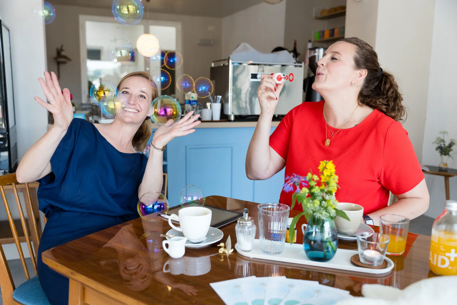 Julia Offenbacher und Eva Panzer, Gründerinnen von ELUVIA Elterncoaching, mit Seifenblasen am Tisch